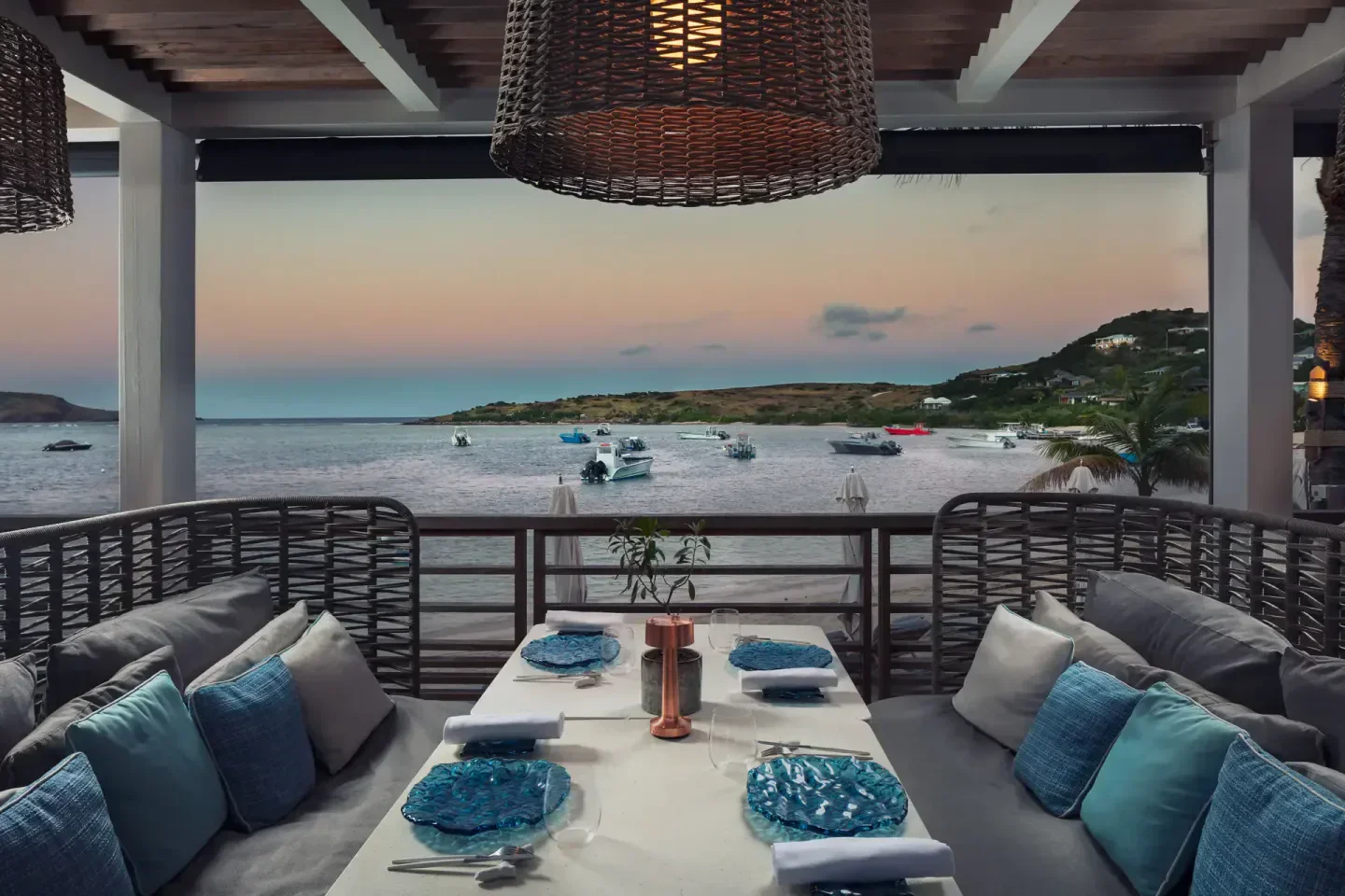 Dining at Amis restaurant in St. Barts with ocean view and boats at sunset.