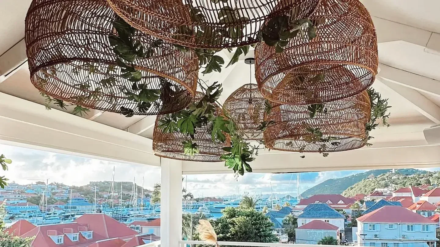 Woven basket lights at Baz Bar in St. Barts with a view of the harbor.