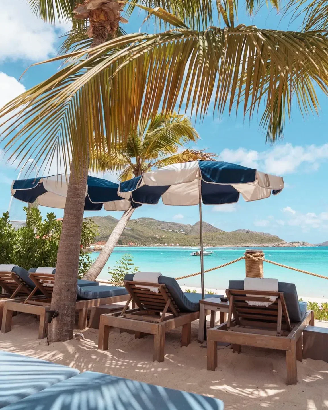 Relaxing beach scene at Gyp Sea Beach in St. Barts with lounge chairs and umbrellas.