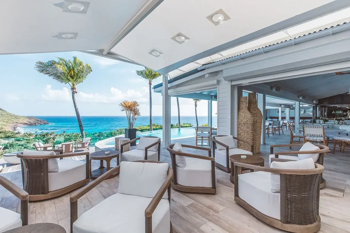 Outdoor seating at Le Toiny Restaurant in St. Barts with ocean views and palm trees